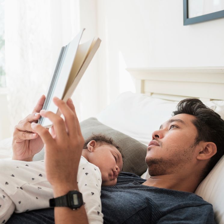 Padre leyendo un libro con su hijo en la cama