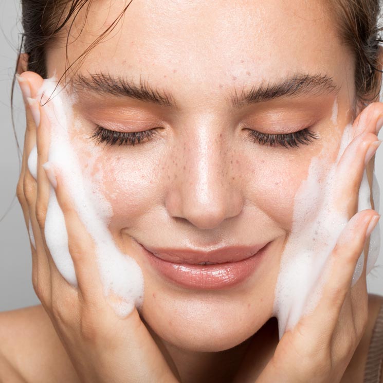 Mujer limpiándose el rostro con gel limpiador en espuma