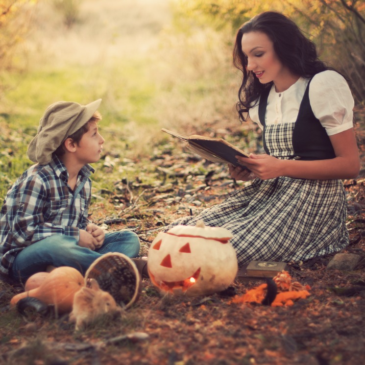 Mujer y niño disfrazados leyendo un libro en Halloween
